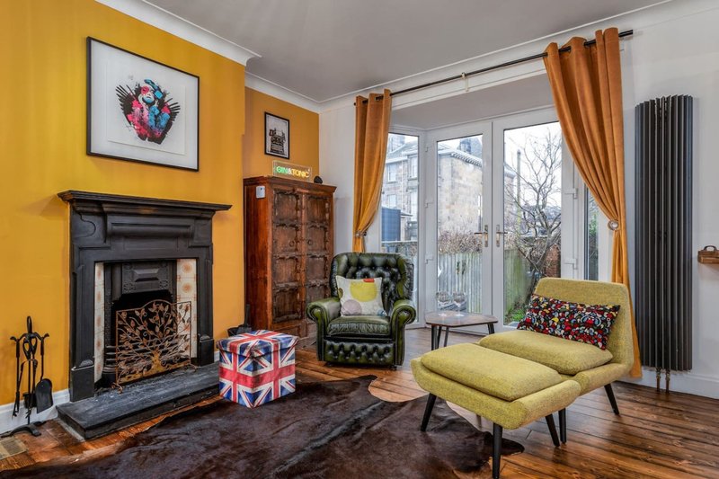 Bright living room with yellow walls, fireplace, green armchair, yellow sofa and garden views