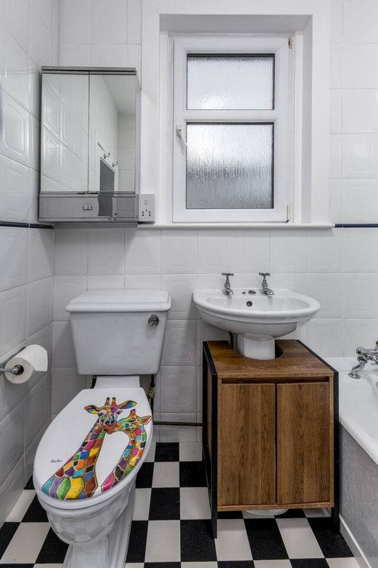 Bathroom with toilet, sink, mirror cabinet, window and black-and-white checkered floor