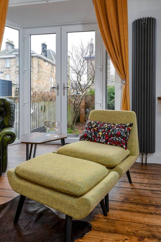 Modern living room with yellow-green armchair, patterned cushion, and garden view through large windows