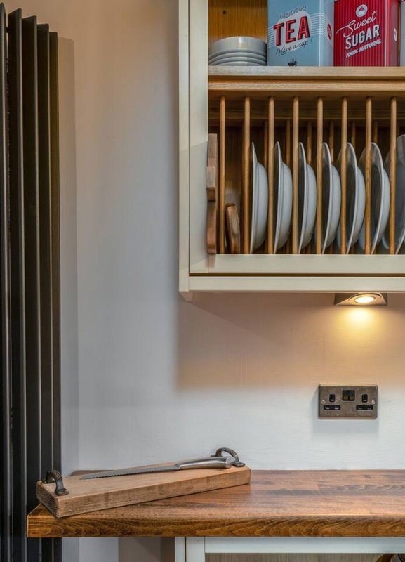 Kitchen shelving with plate rack, tea and sugar containers, wooden countertop and radiator