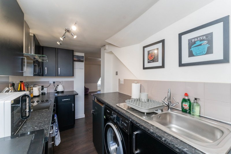 Kitchen and laundry area with black cabinetry, sink, washing machine and framed wall art