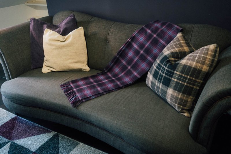 Gray upholstered sofa with decorative cushions and tartan throws