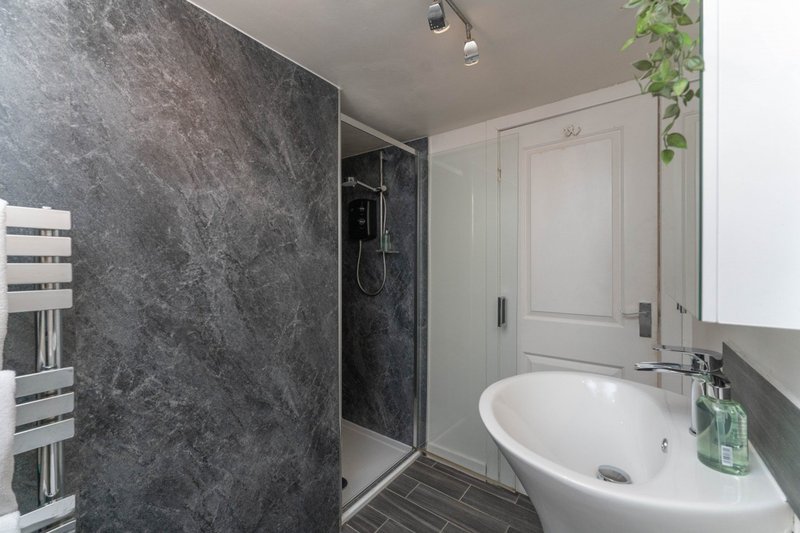 Modern bathroom with walk-in shower, round white basin, and heated towel rail