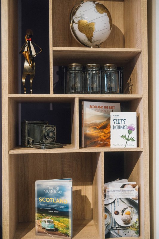 Wooden shelving unit displaying globe, books, vintage camera, glass jars, and decorative items