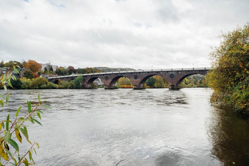 River view from property with historic stone bridge and autumn foliage