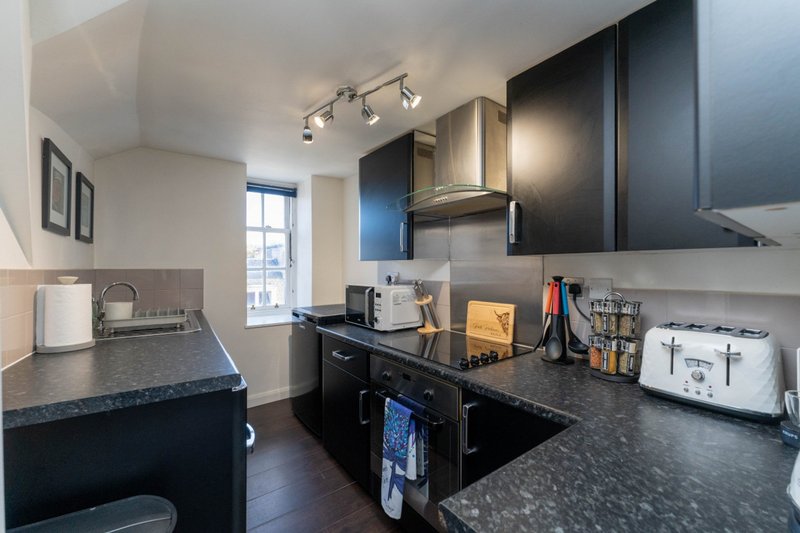 Modern kitchen with black cabinetry, dark countertops, stainless steel appliances and pendant lighting