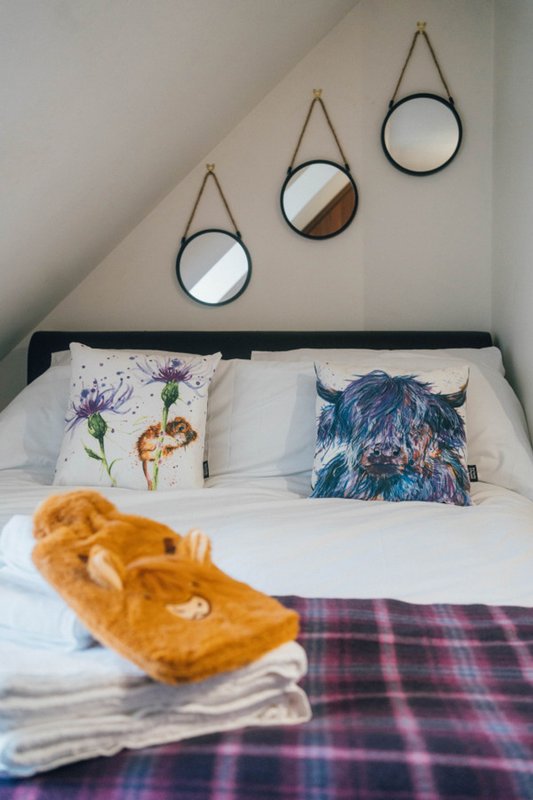 Bedroom with double bed, decorative wall mirrors, patterned pillows and plaid bedding