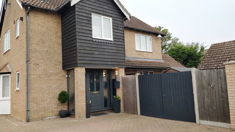 Modern brick house with black garage door, driveway, and front entrance with potted plants