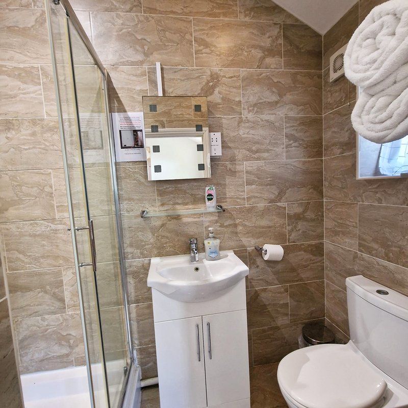 Modern bathroom with brown tile walls, white sink vanity, toilet, and glass shower enclosure