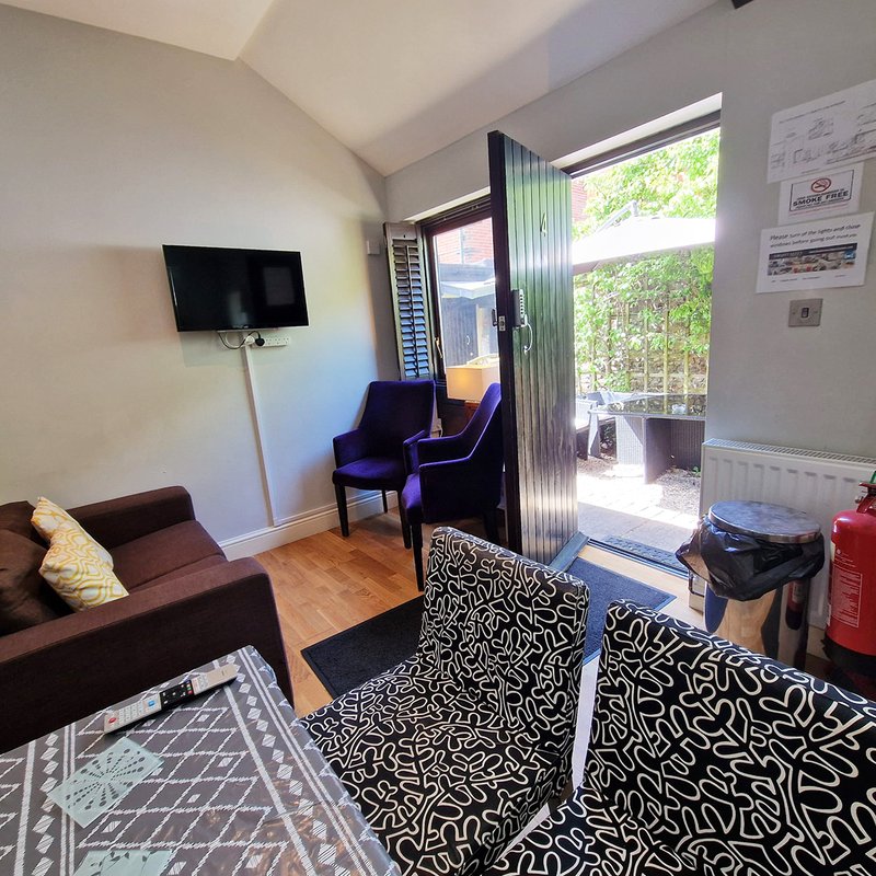 Living room with sofa, armchair, wall-mounted TV, patio doors and wooden flooring