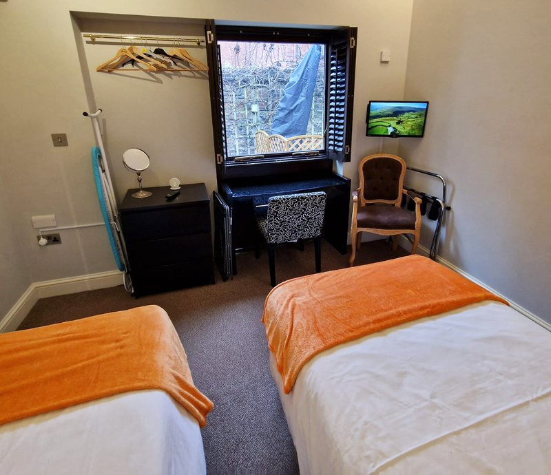 Bedroom with two single beds, desk with computer monitor, chair, and wall-mounted TV