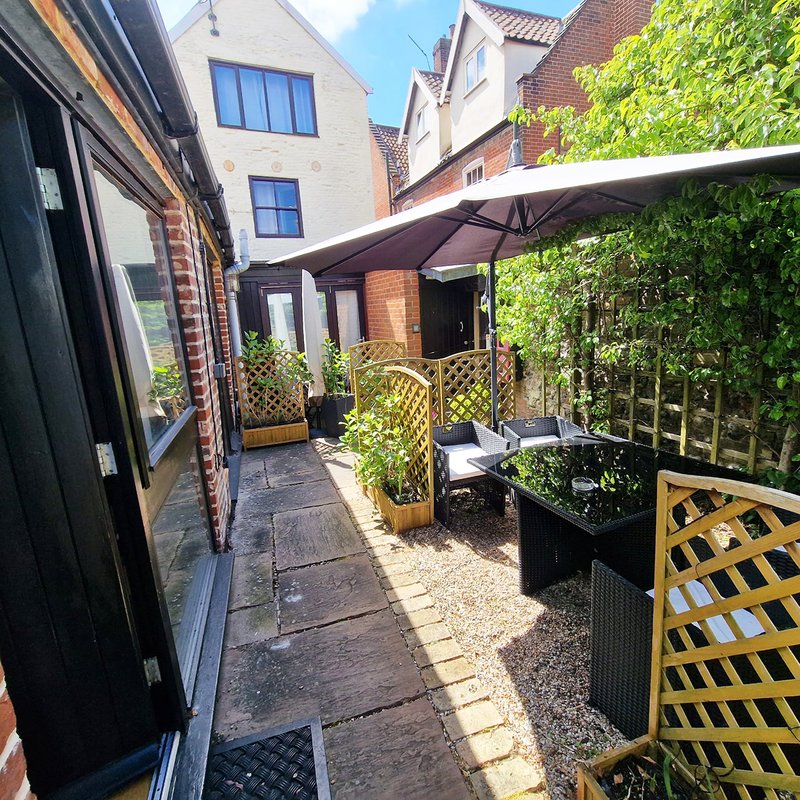 Patio garden with black awning, yellow trellis panels, potted plants and seating area
