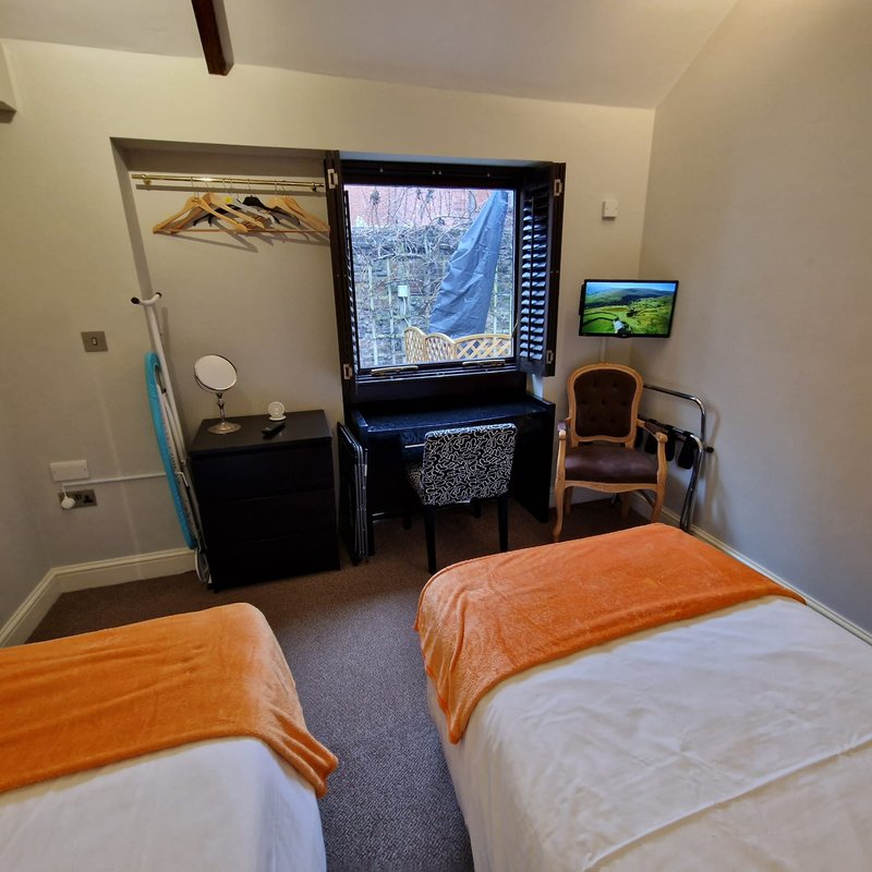 Bedroom with two single beds, desk with computer monitor, chair, and bathroom door