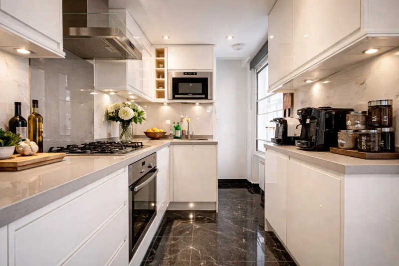 Modern white kitchen with gas hob, integrated appliances, wooden countertops and dark flooring