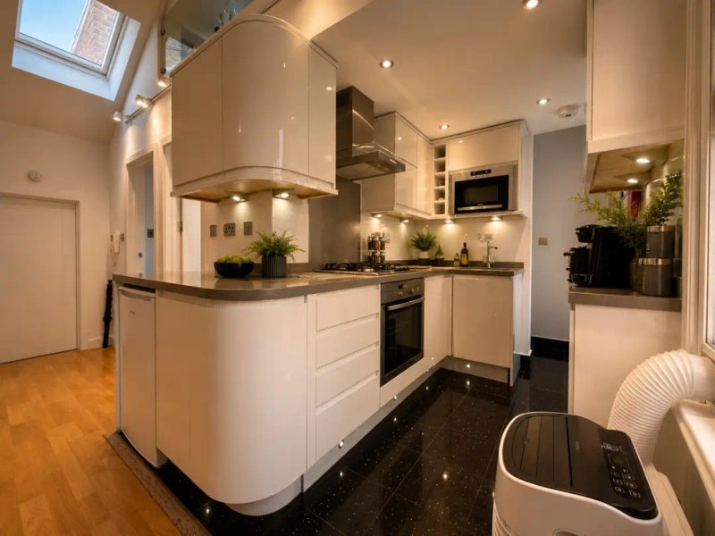Modern kitchen with white cabinetry, curved island, stainless steel appliances and skylight