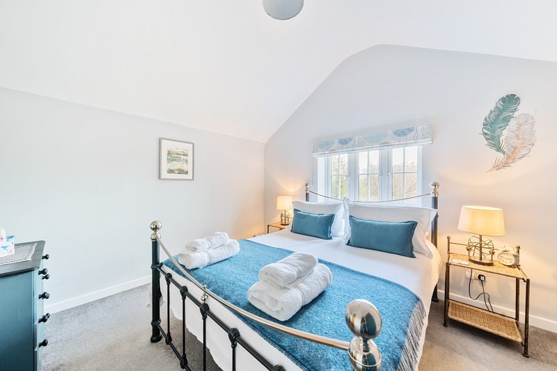 Bright attic bedroom with blue bedding, white pillows, metal bed frame and sloped ceiling