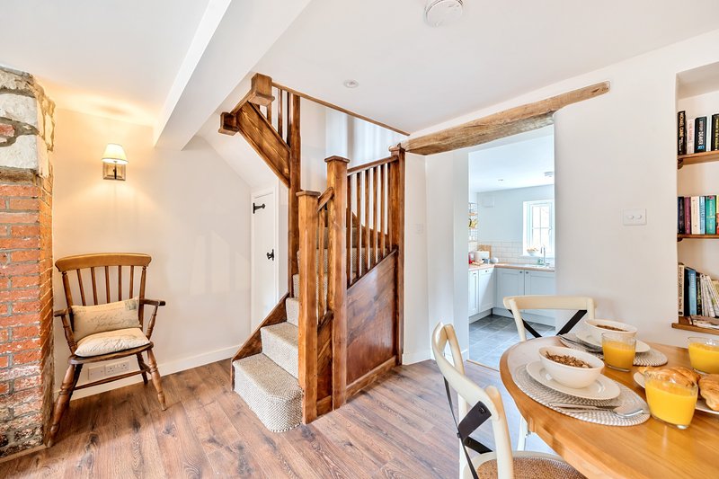 Open-plan living area with wooden staircase, dining table set for dining, and armchair