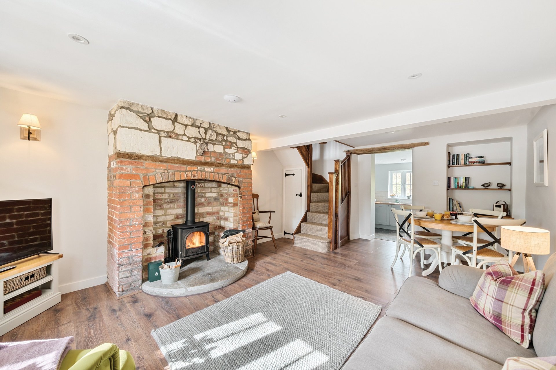 Open-plan living room with wood-burning stove, brick fireplace, sofa, and dining area beyond