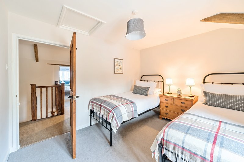Bright bedroom with two single beds, wooden nightstand, metal bed frames and ceiling light
