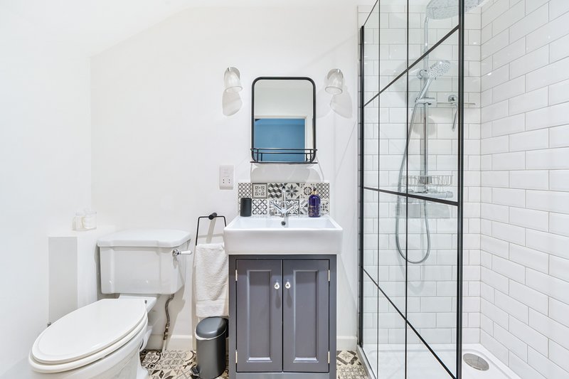 Modern bathroom with white subway tiles, dark vanity, mirror, and glass shower enclosure