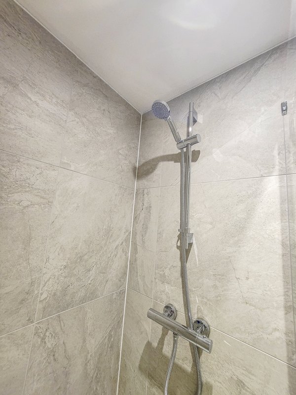 Modern bathroom shower with rainfall showerhead, handheld spray, and tiled walls