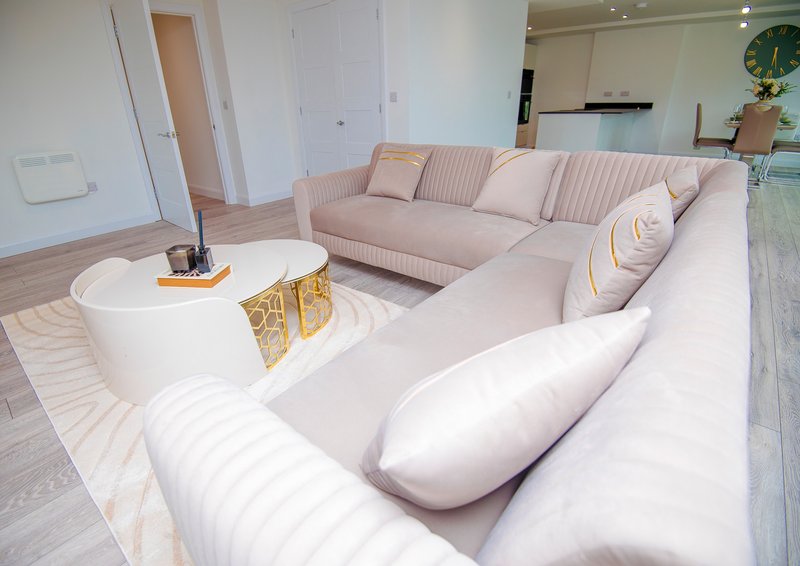 Modern living room with cream curved sectional sofa, white side table, and wooden flooring