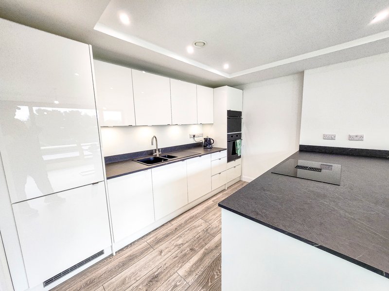 Modern kitchen with white cabinets, black countertops, island, and wooden flooring