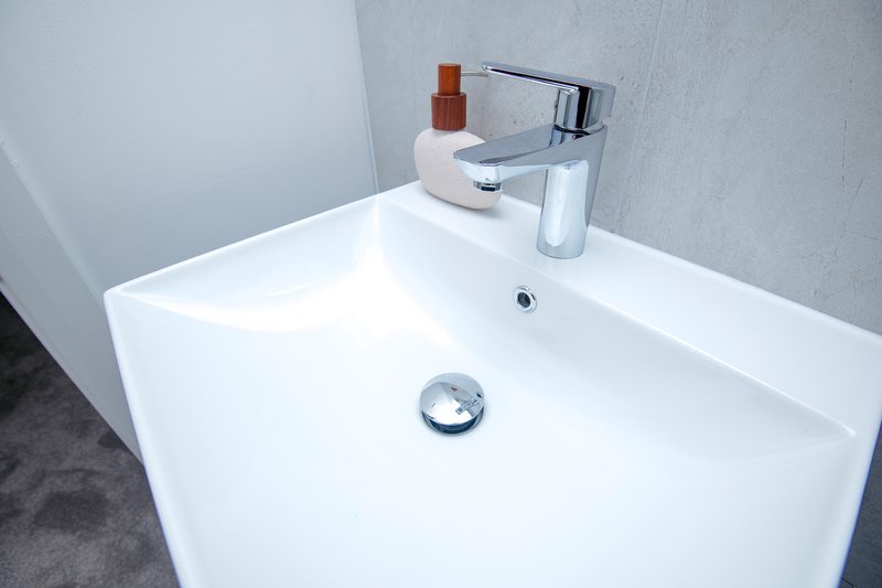 Modern bathroom sink with chrome faucet, soap dispenser and toiletries