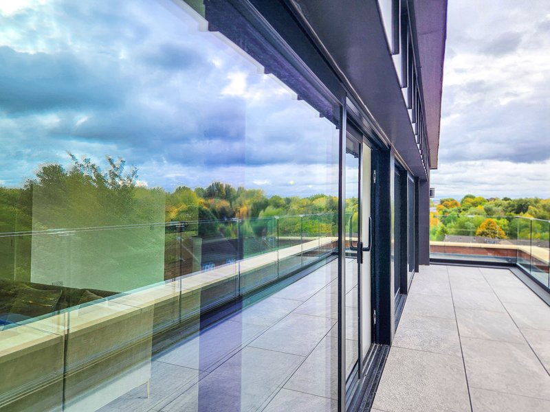 Modern balcony with glass railings overlooking countryside landscape and sky