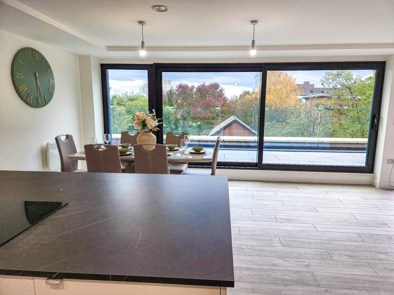 Modern open-plan kitchen and dining area with large windows overlooking garden and landscape