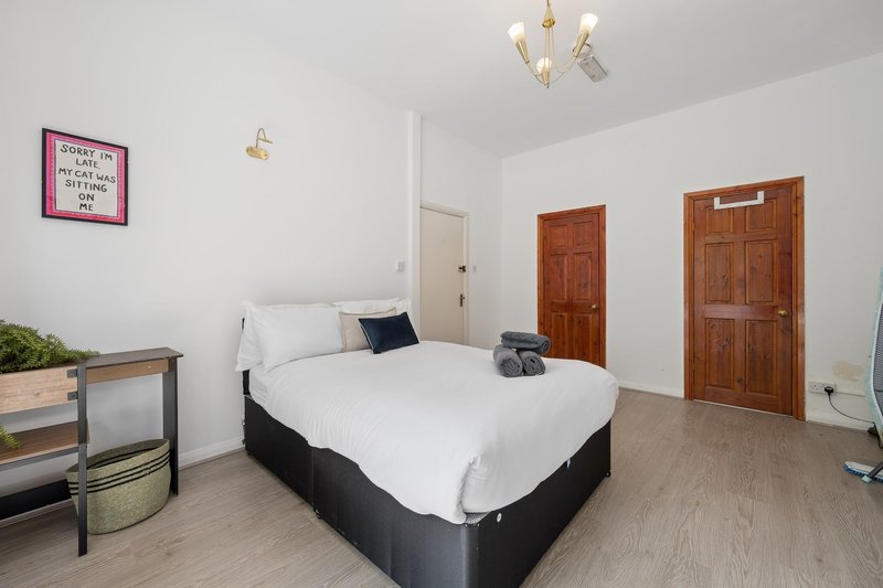 Bright bedroom with double bed, wooden doors, pendant lights and bedside furniture
