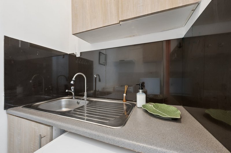 Modern kitchen with stainless steel sink, black splashback, and grey countertop