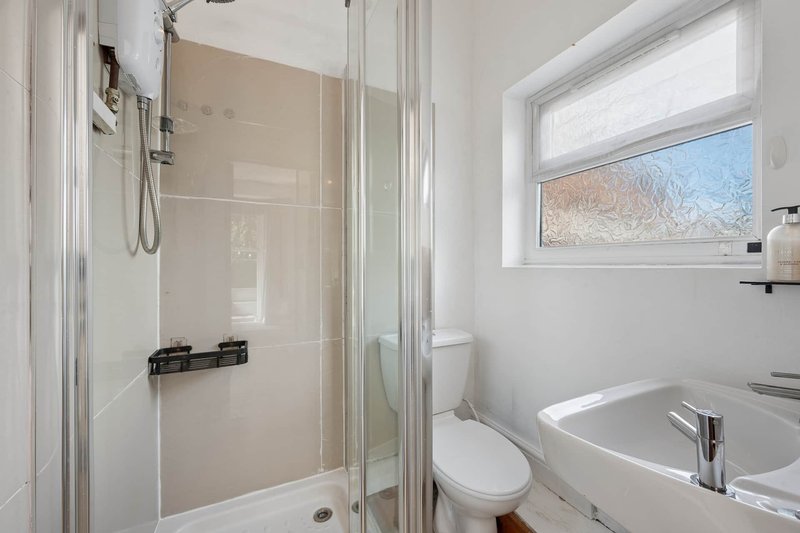 Modern bathroom with walk-in shower, white toilet, sink and window with view