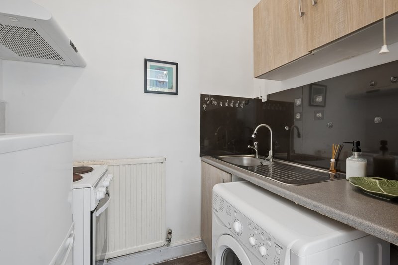 Modern kitchen with black backsplash, stainless steel sink, washing machine and white appliances