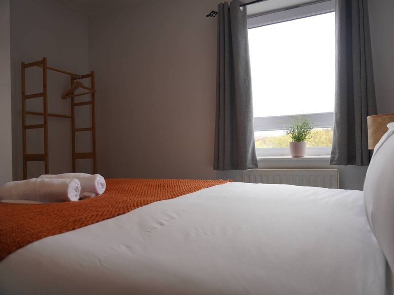 Bedroom with double bed, orange runner, wooden room divider and window with countryside view