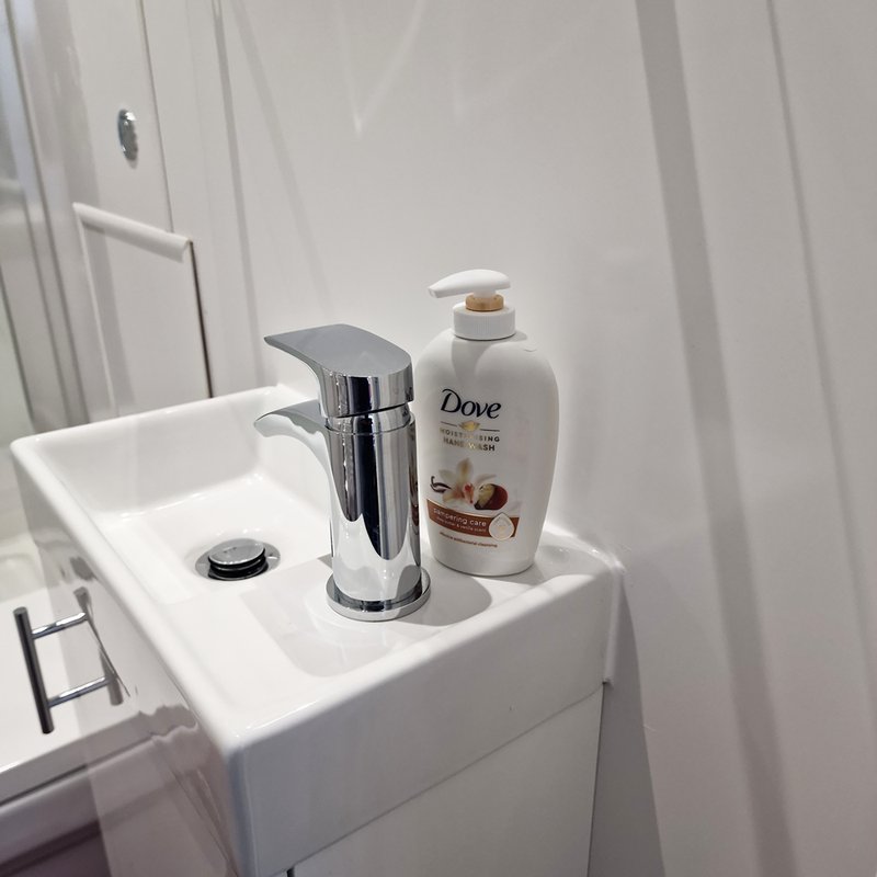 Bathroom sink with chrome tap, white basin, soap dispenser and toiletries