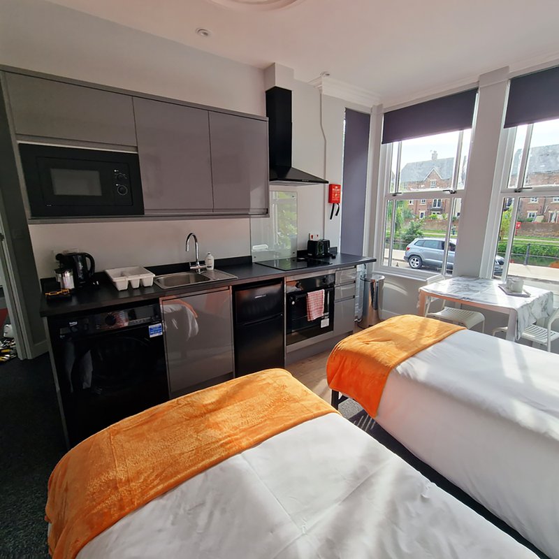 Modern kitchen-diner with grey cabinetry, black appliances, dining table and windows overlooking street