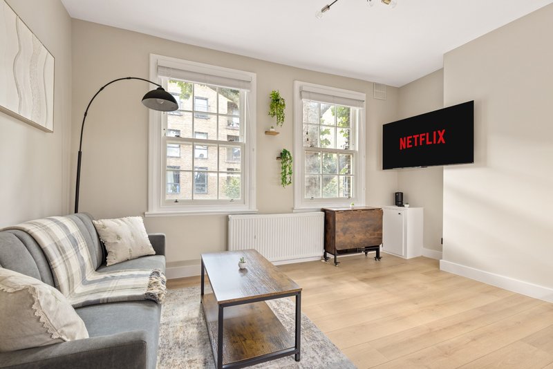 Bright living room with sofa, coffee table, arc lamp, TV mounted on wall, and large windows