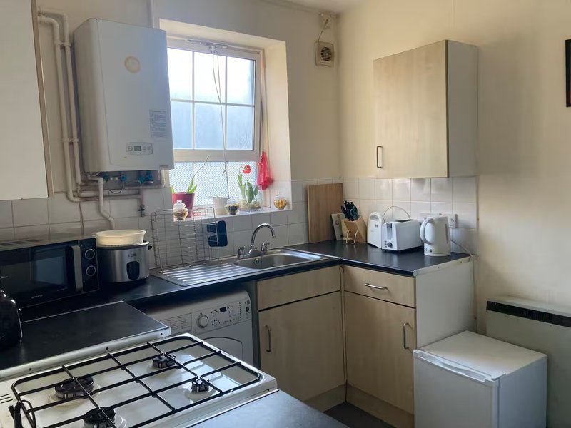 Compact kitchen with gas cooker, sink, window and white boiler above counter