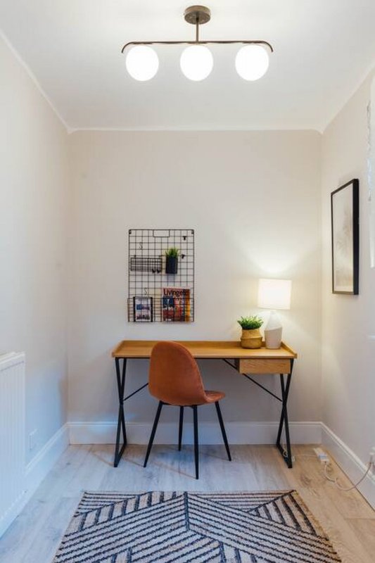 Home office nook with wooden desk, orange chair, wall-mounted grid organizer and framed art