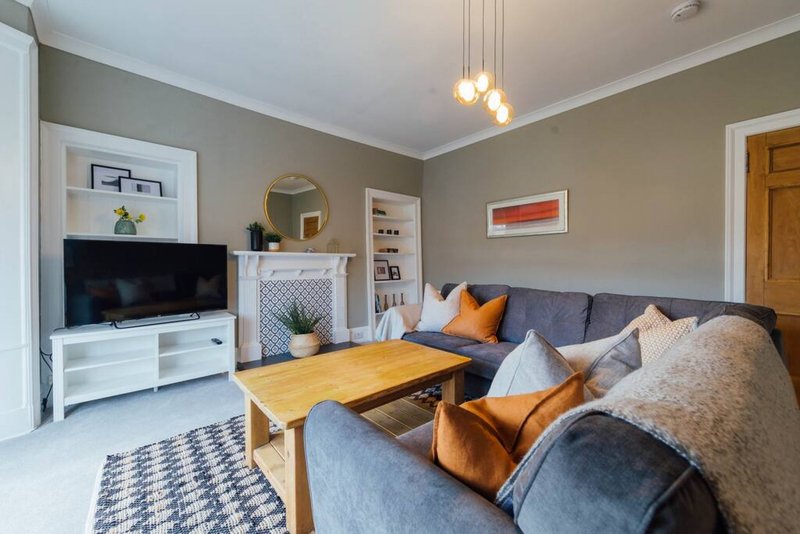 Living room with grey sofa, wooden coffee table, TV unit, and pendant lighting