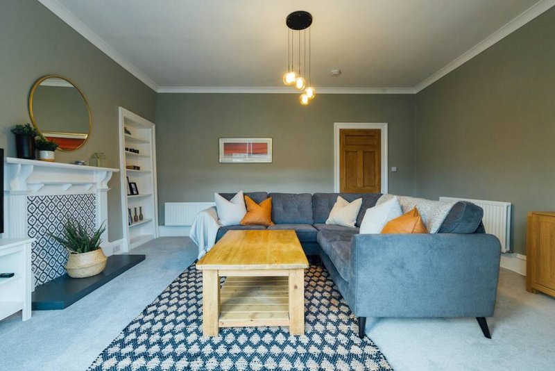 Modern living room with blue sofa, fireplace, wooden coffee table and pendant lighting