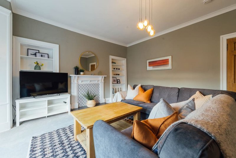 Modern living room with gray sofa, wooden coffee table, TV unit, and fireplace