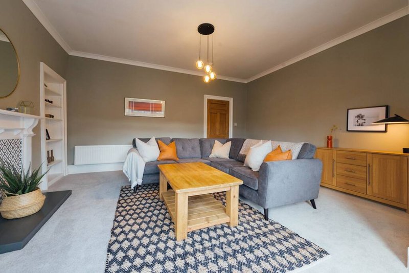 Modern living room with grey sofa, wooden coffee table, patterned rug and pendant lighting