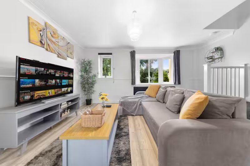 Modern living room with grey sofa, TV unit, wooden coffee table and yellow accents