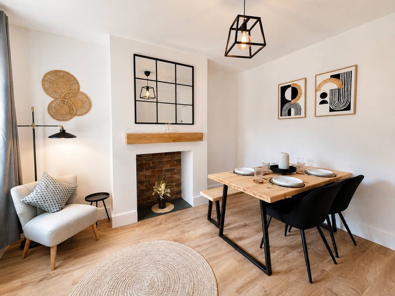 Open-plan living and dining area with fireplace, dining table, cream armchair, and wall art