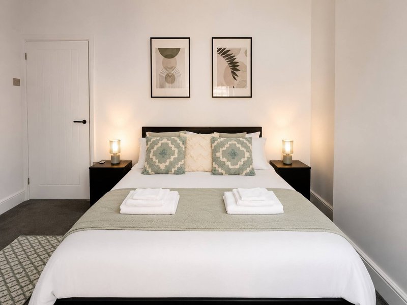 Modern bedroom with double bed, black headboard, geometric patterned pillows, and wall art