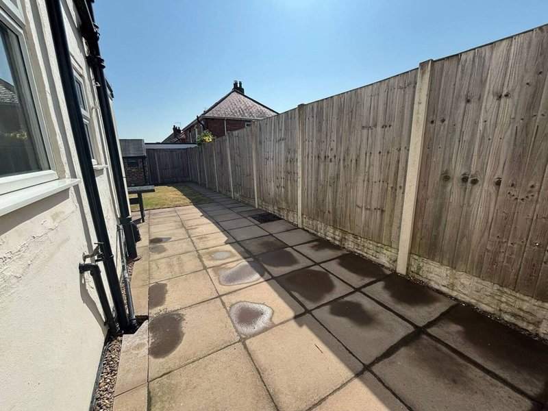 Outdoor patio area with wooden fencing, paved ground, and views of neighboring properties