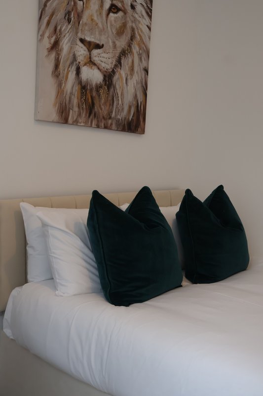 Bedroom with white bedding, black velvet cushions, and lion artwork on wall
