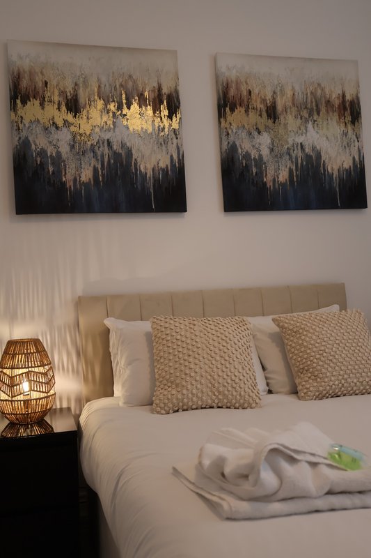 Bedroom with upholstered headboard, white bedding, decorative pillows and abstract wall art